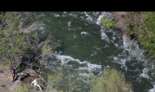 People walk along the Provo River as a search for a missing child in the river continues, downstrea...