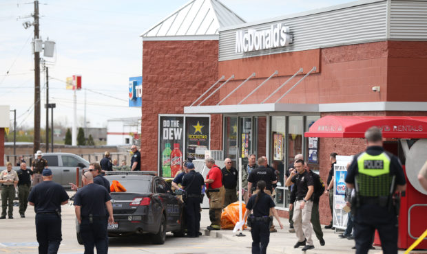 Law enforcement and fire officials convene at a scene where two officers and one suspect were injur...