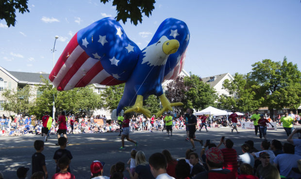 A large American-themed eagle blow-up passes by the crowd at the annual Grand Parade in downtown Pr...