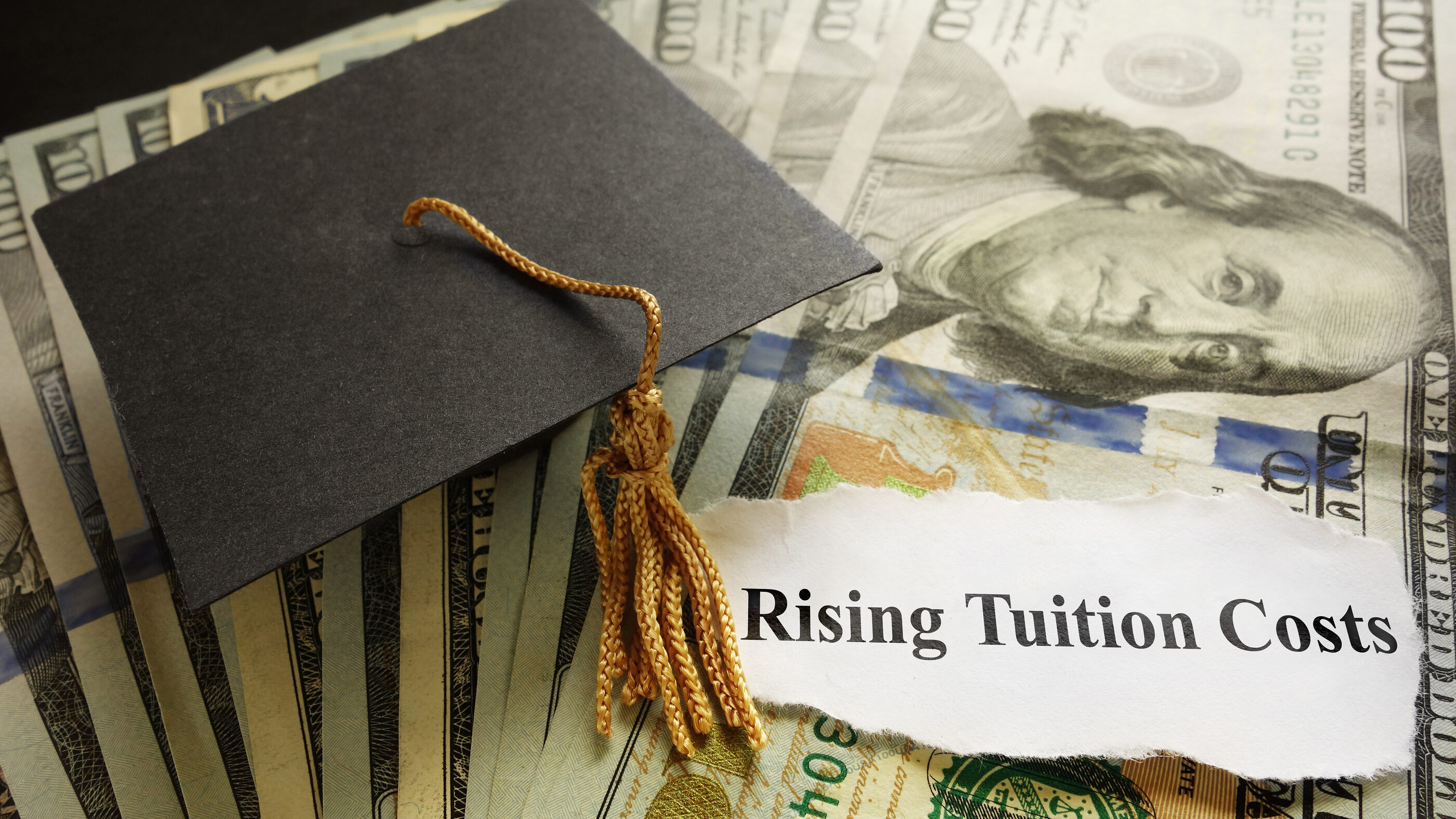 A graduation cap is pictured on a pile of money with text reading "rising tuition costs....