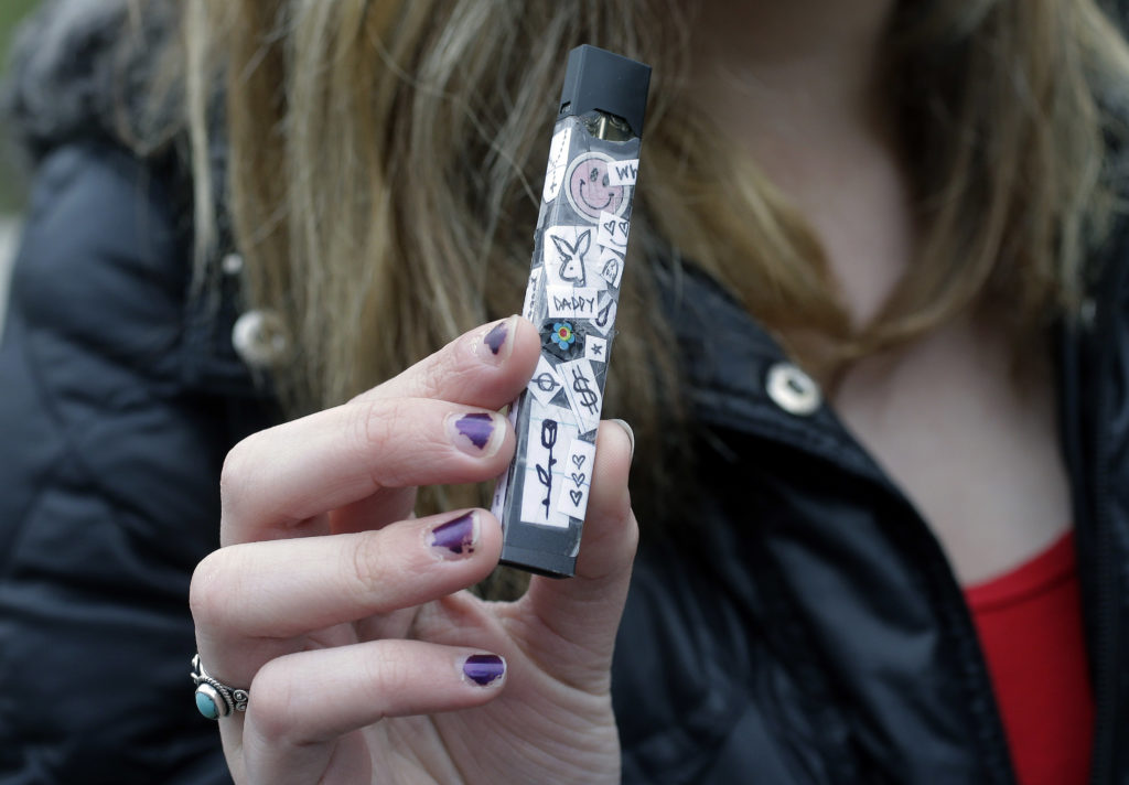 A young smoker uses a Juul e-cigarette.