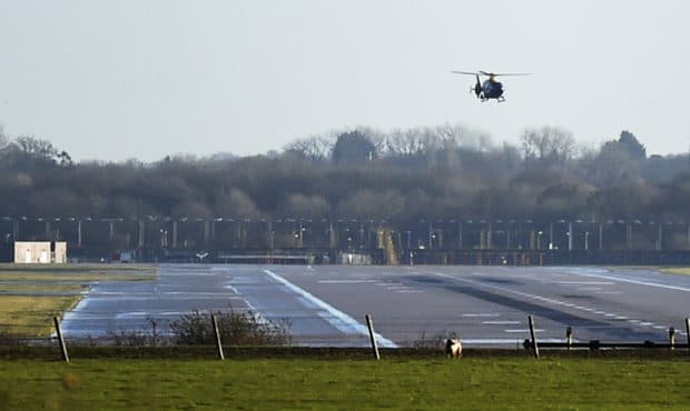 A police helicopter flies over the runway at Gatwick airport, London, as the airport remains closed...