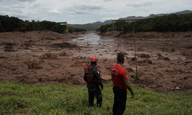 Civil firefighters survey a destroyed rail bridge two days after a dam collapse in Brumadinho, Braz...