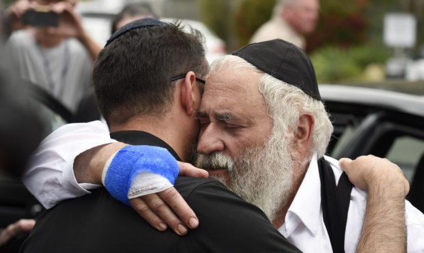 Rabbi Yisroel Goldstein, right, is hugged as he leaves a news conference at the Chabad of Poway syn...