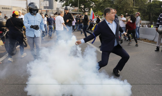 An opponent to Venezuela's President Nicolas Maduro returns a tear gas canister in Caracas, Venezue...