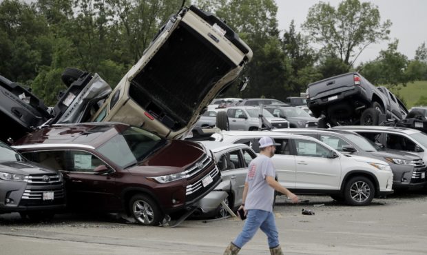 A worker walks past tornado-damaged Toyotas at a dealership in Jefferson City, Mo., Thursday, May 2...