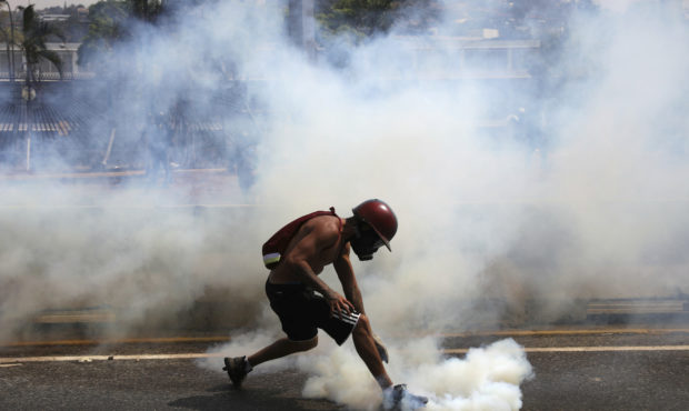 An anti-government protester grabs a tear gas canister launched by National Guard forces outside La...