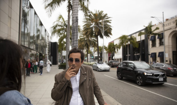 Visiting from France, Meyer Joseph, center, smokes a cigarette in front of luxury shops while talki...