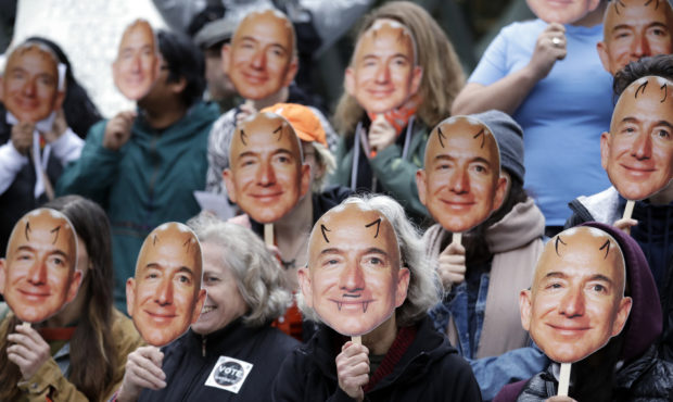 FILE - In this Oct. 31, 2018, file photo, demonstrators hold images of Amazon CEO Jeff Bezos near t...