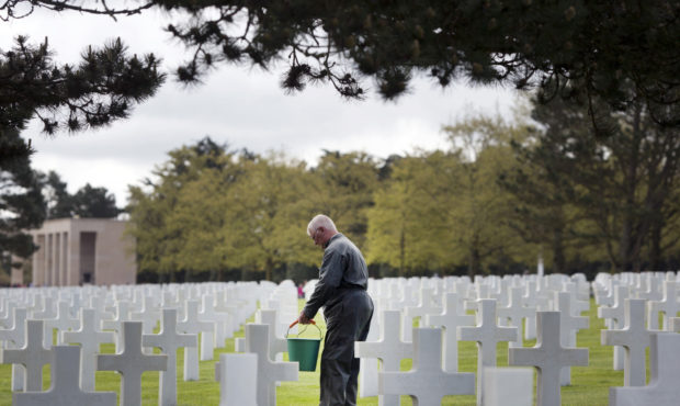 In this May 2, 2019, photo, a worker cleans moss off the headstones of World War II soldiers at the...