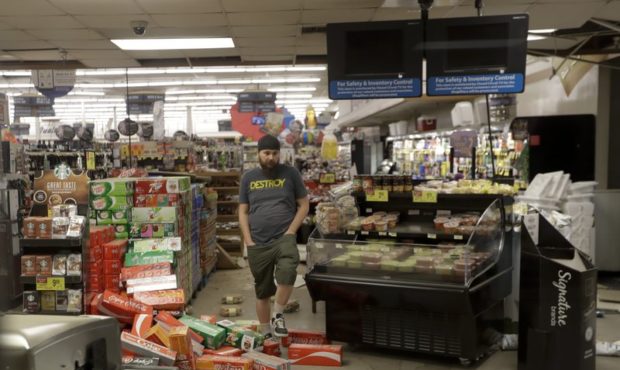 A worker steps over merchandise that is scattered on the floor of a Albertson's grocery store Satur...