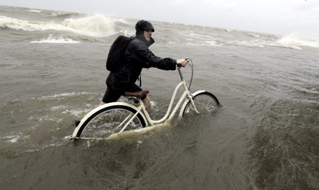 Tyler Holland guides his bike through the water as winds from Tropical Storm Barry push water from ...