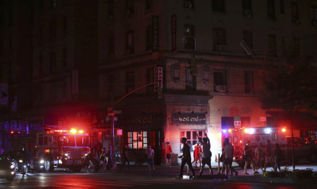 Pedestrians cross the street near emergency response vehicles at 50th Street and 8th Avenue during ...