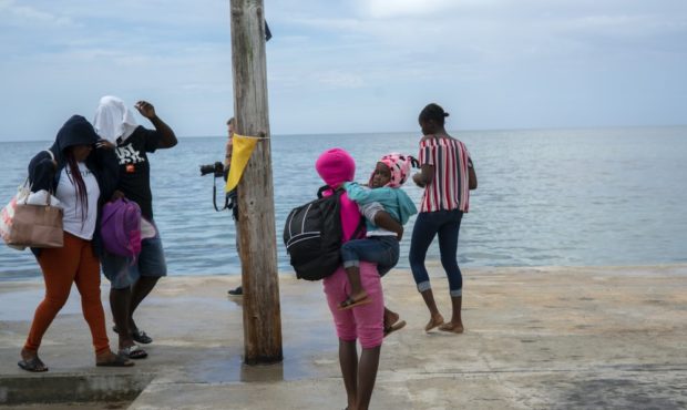 A woman carries a girl in her arms after being evacuated from a nearby Cay due to the danger of flo...