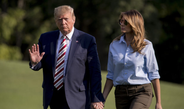 President Donald Trump waves to members of the media as he and first lady Melania Trump walk across...