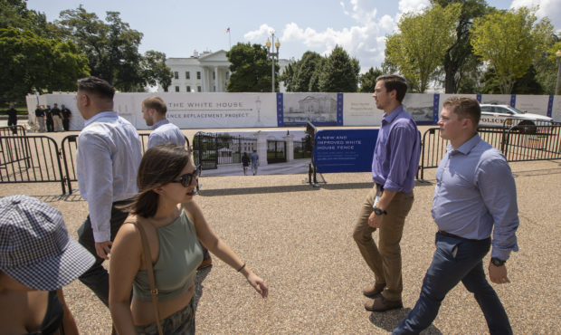 Visitors and office workers from nearby walk in front of the White House in Washington with the new...
