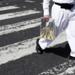 A fan carries a copy of the album 'Abbey Road' as he crosses the Abbey Road zebra crossing on the 50th anniversary of British pop musicians The Beatles doing it for their album cover of 'Abbey Road' in St Johns Wood in London, Thursday, Aug. 8, 2019. They aimed to cross 50 years to the minute since the 'Fab Four' were photographed for the album cover. (AP Photo/Kirsty Wigglesworth)