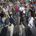 Thousands of fans gather to walk across the Abbey Road zebra crossing, on the 50th anniversary of British pop musicians The Beatles doing it for the cover of their album 'Abbey Road' in St Johns Wood in London, Thursday, Aug. 8, 2019. They aimed to cross 50 years to the minute since the 'Fab Four' were photographed for the album.(Dominic Lipinski/PA via AP)