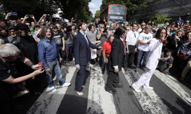 Fans dressed as lookalikes walk across the Abbey Road zebra crossing on the 50th anniversary of Bri...
