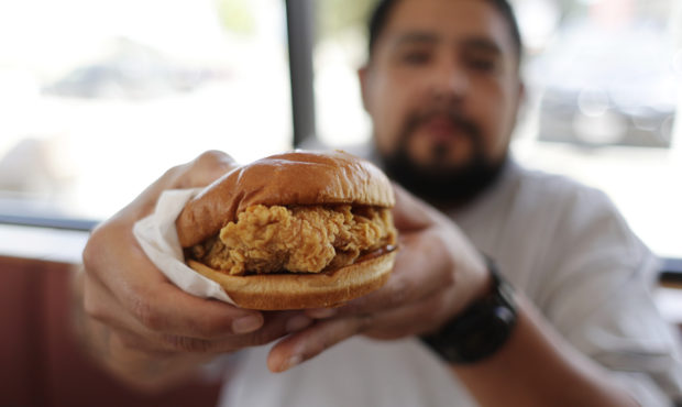 Randy Estrada holds up his chicken sandwiches at a Popeyes, Thursday, Aug. 22, 2019, in Kyle, Texas...