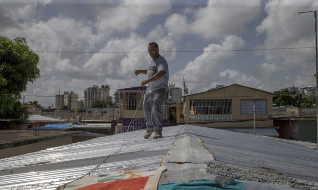 Jorge Ortiz works to tie down his roof as he prepares for the arrival of Tropical Storm Dorian, in ...