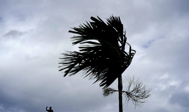 A man stands on a store's roof as he works to prepare it for the arrival of Hurricane Dorian in Fre...