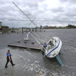 Beaufort Police Officer Curtis Resor, left, and Sgt. Micheal Stepehens check a sailboat for occupants in Beaufort, N.C. after Hurricane Dorian passed the North Carolina coast on Friday, Sept. 6, 2019. Dorian howled over North Carolina's Outer Banks on Friday — a much weaker but still dangerous version of the storm that wreaked havoc in the Bahamas — flooding homes in the low-lying ribbon of islands and throwing a scare into year-round residents who tried to tough it out.  (AP Photo/Tom Copeland)