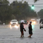 Two men wade across 19th Street in Galveston, Texas., Wednesday, Sept. 18, 2019 as heavy rain from Tropical Storm Imelda caused street flooding on the island. (Jennifer Reynolds/The Galveston County Daily News via AP)