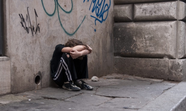Young boy huddled and alone on a city street. Photo courtesy of Getty Images....