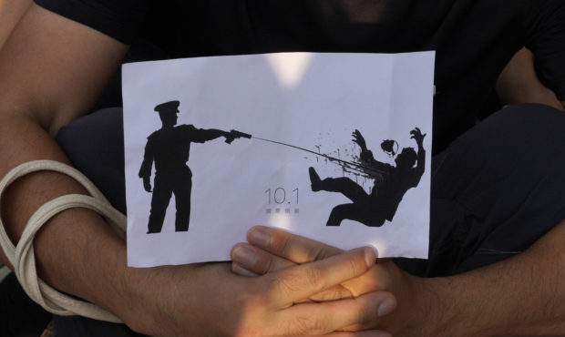 A supporter holds a printing featuring a protester being shot in the chest by police during a strik...