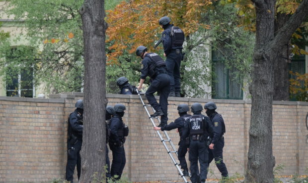 Police officers cross a wall at a crime scene in Halle, Germany, Wednesday, Oct. 9, 2019 after a sh...