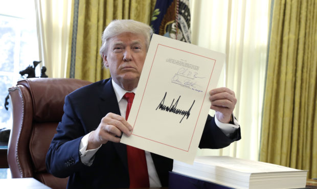 FILE - In this Dec. 22, 2017, file photo, President Donald Trump displays the $1.5 trillion tax ove...