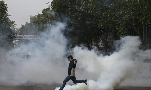 A protester kicks a tear gas canister launched by police during a protest in Santiago, Chile, Satur...