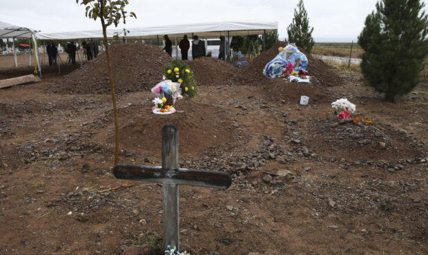 Freshly dug graves, top of photo, are prepared for Rhonita Miller, 30, and four of her young childr...