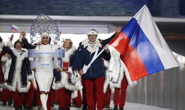 FILE - In this Feb. 7, 2014 file photo Alexander Zubkov of Russia carries the national flag as he l...