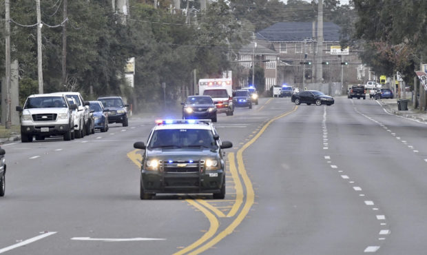Police cars escort an ambulance after a shooter open fire inside the Pensacola Air Base, Friday, De...