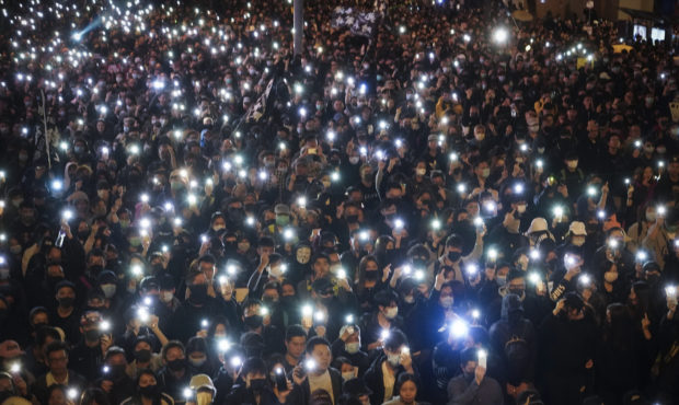 Pro-democracy protesters flash their smartphones lights as they gather on a street in Hong Kong, Su...
