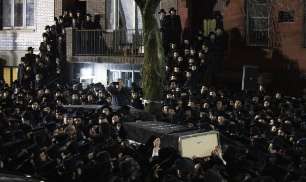 Orthodox Jewish men carry Moshe Deutsch's casket outside a Brooklyn synagogue following his funeral...