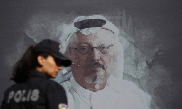 FILE - In this Oct. 2, 2019 file photo, a Turkish police officer walks past a picture of slain Saud...