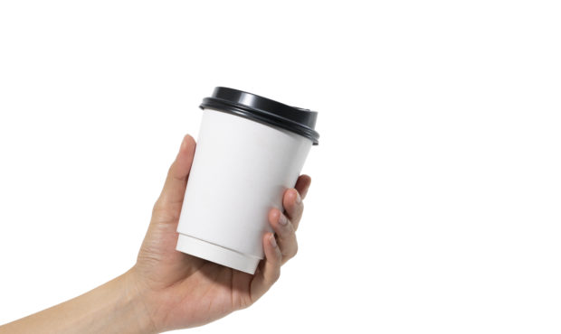 female hand holding a coffee paper cup isolated on white background....