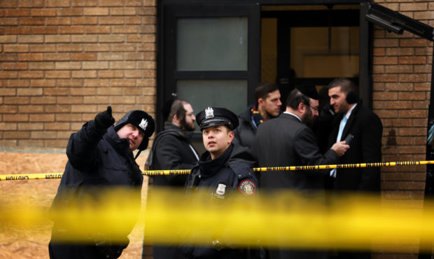 JERSEY CITY, NJ - DECEMBER 11: Police officers look at bullet holes in the windows of a school acro...