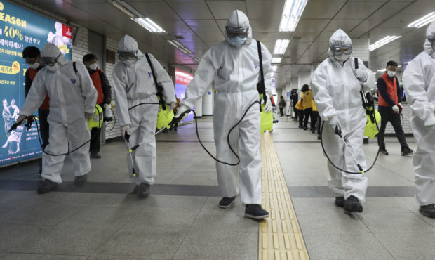 Workers wearing protective gears disinfect as a precaution against the new coronavirus at the subwa...