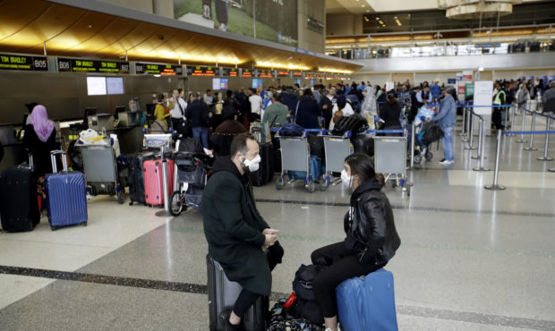 FILE - In this Saturday, March 14, 2020 file photo, travelers wait to check in their luggage at the...