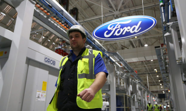 An employee walks past a Ford logo in the yet-to-be-completed engine production line at a Ford fact...