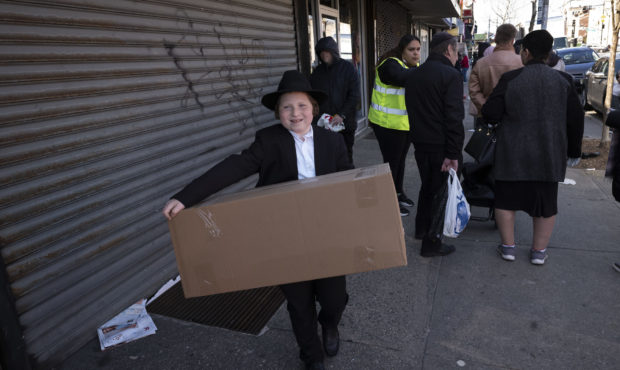 FILE - In this Thursday, March 26, 2020 file photo, a boy carries a box of matzos for Passover that...