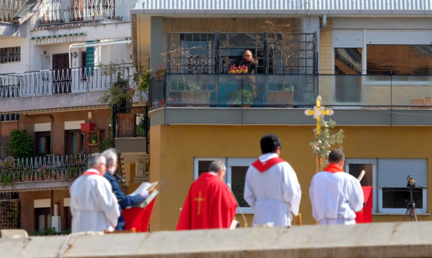 A faithful from a facing balcony follows the celebration of the Palm Sunday mass on the roof of the...