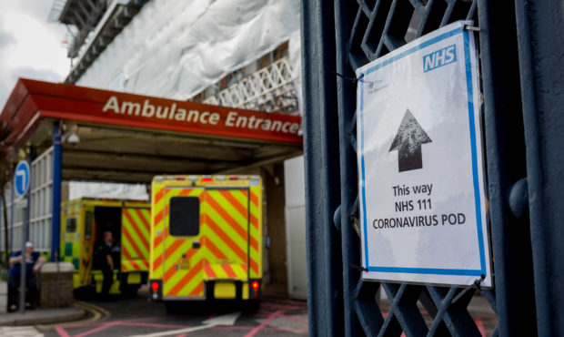 An NHS sign points towards a Coronavirus testing pod, as an ambulance arrives at the A&E Depart...