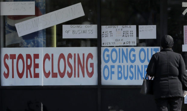 A woman looks at signs at a store closed due to COVID-19 in Niles, Ill., Wednesday, May 13, 2020. (...