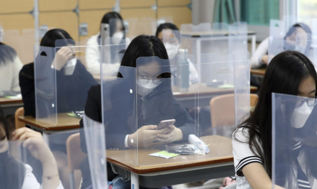 FILE -- Senior students wait for class to begin with plastic boards placed on their desks at Jeonmi...