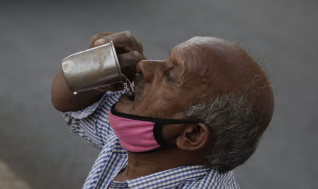 An Indian man selling earthen pots beneath a bridge drinks water in Ahmedabad, India, Thursday, May...